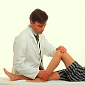 GP examining a teenage boy's leg and knee