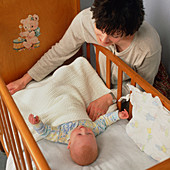 Cot death prevention: mother puts baby to bed