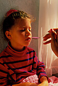 Sick young girl is fed a spoon of medicine