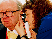 Nurse using otoscope to examine man's ear