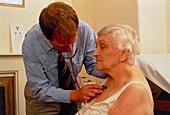 Doctor with a stethoscope examines elderly woman