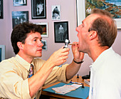 Doctor examines a man's throat