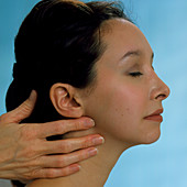 GP palpating the lymph glands of a young woman