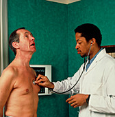 GP doctor listens to man's heart using stethoscope