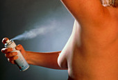 Woman using aerosol underarm deodorant