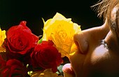 Profile of woman smelling red and yellow roses