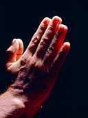 Side view of man's hands held together in prayer