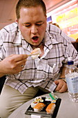 Obese man eating sushi