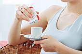 Woman adding sweetener to coffee