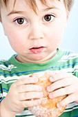 Toddler eating a jam doughnut