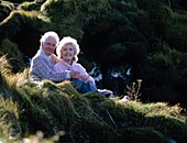 Elderly couple on a grassy slope in countryside