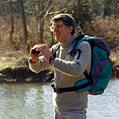 Middle-aged male hiker using binoculars