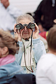 Elderly woman uses binoculars