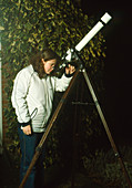 Astronomer using a refractor telescope