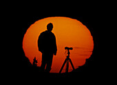A photographer upon the solar disc at sunset