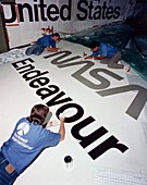 Painting insignia on wing of Shuttle Endeavour
