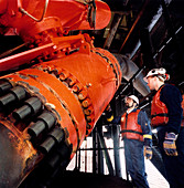 Technicians inspect a pipe on an oil rig