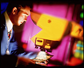 Technician checking circuit board under microscope
