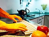 Gloved hands using computer keyboard in a kitchen