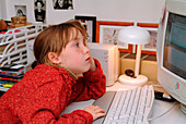 Tired girl working at a home computer