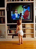 Child watches television using remote control