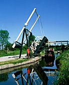 Barge passing under a manually raised bridge