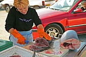Market trader slicing fish