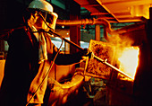 Steel worker checking contents of furnace