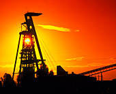 Head frame over shaft of gold mine at sunset