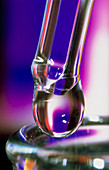Droplet hanging from pipette above test tube neck
