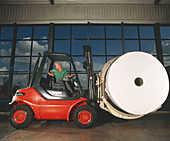 Worker with fork lift truck in a paper mill