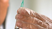 Nurse tapping and squeezing syringe