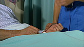 Nurse taking patient's pulse in bed