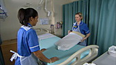 Nurses making hospital bed