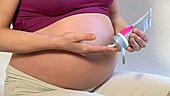 Pregnant woman applying skin cream