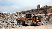 Excavator carrying rubble in a quarry