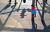 A little girl at a playground climbing a pole
