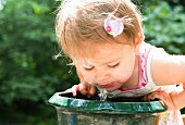 Kleines Mädchen löscht seinen Durst an Trinkbrunnen