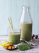 Two green smoothies garnished with turmeric and hazelnuts