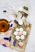 Pink and white meringues in glass dish next to cup of tea