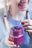 A woman with a blackberry and blueberry smoothie