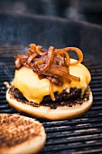 Hamburger mit Käse und Röstzwiebeln auf dem Grillrost