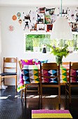 Esstisch mit bunter Tischdecke und geometrischem Muster, Retro Holzstühle, Wanddekoration mit angehefteten Fotos über Fenster