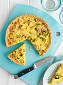 Leek and bacon quiche on the blue chopping board, sliced
