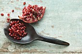 A pomegranate wedge and pomegranate seeds on a spoon