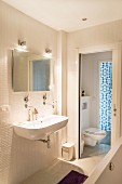 Badezimmer mit weißen Mosaikfliesen und Schiebetür zum WC