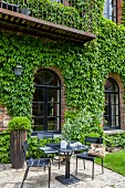 Seating area outside brick building with Virginia creeper on wall