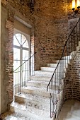 Curved stone staircase against rustic brick wall