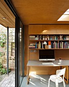 Computer on desk in modern extension with wood cladding, skylight and open terrace doors