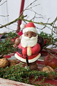 Chocolate Father Christmas amongst juniper branches and nuts